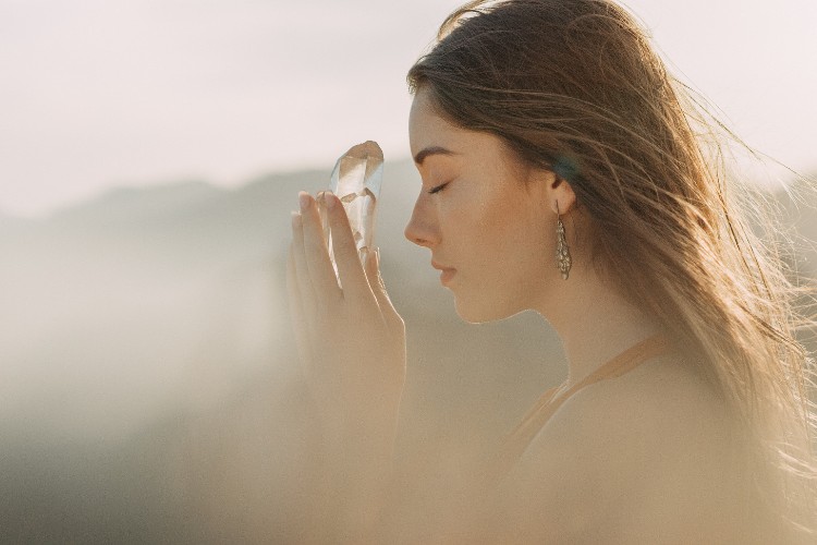 young woman at peace while holding a crystal close to her face