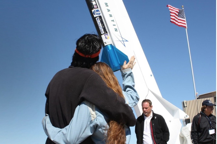 couple waving farewell to a space rocket