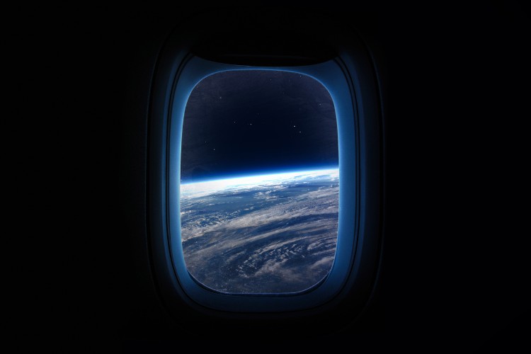 View of Earth from space through a spacecraft window, showcasing the planet's curvature against the dark expanse of space