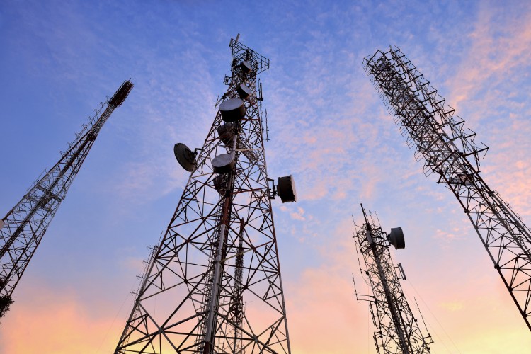 Telecommunications towers reaching into a colorful sky at dusk