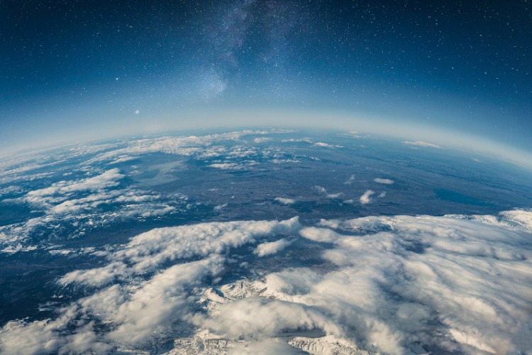 A breathtaking view of Earth from space, showcasing clouds, land, and a starry sky in the background