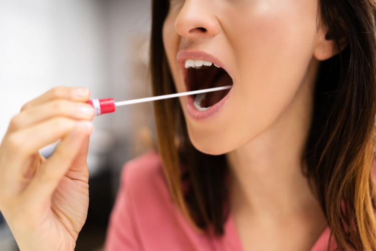 Close-up of a person collecting a saliva sample with a swab, illustrating a non-invasive DNA collection process