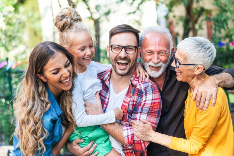 Three generations of a family smiling and embracing outdoors, symbolizing the legacy aspect of DNA banking