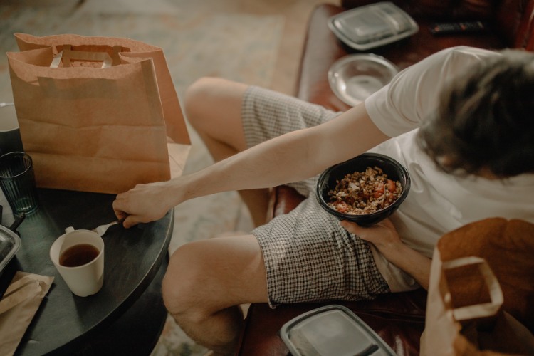 Grieving person eating takeout food sent by a concerned friend