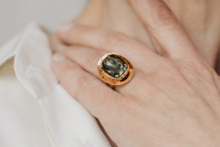 A close-up of a gold ring with a gemstone, symbolizing memorial engraved jewelry