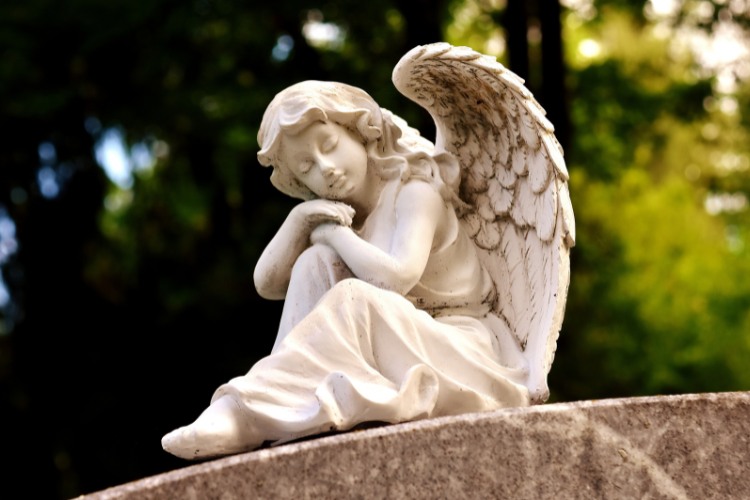 A garden memorial stone adorned with an angel sculpture