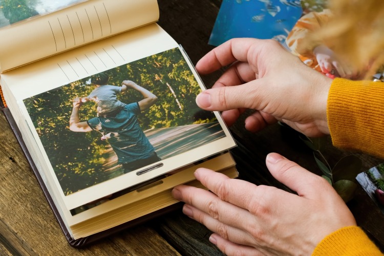 Hands flipping through a photo album of a deceased loved one