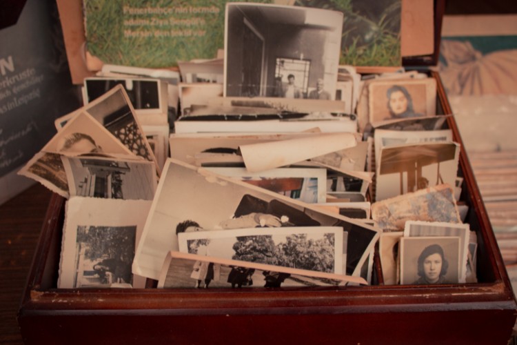 A collection of faded photographs stored in a memory box, symbolizing a tribute to a veteran through preserved personal history